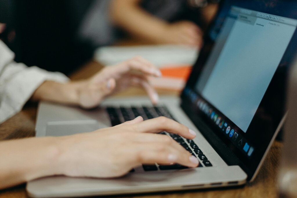 Person typing on a laptop in an office setting. Focus on hands and keyboard.